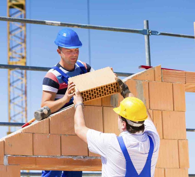 Construction site workers handing each other bricks